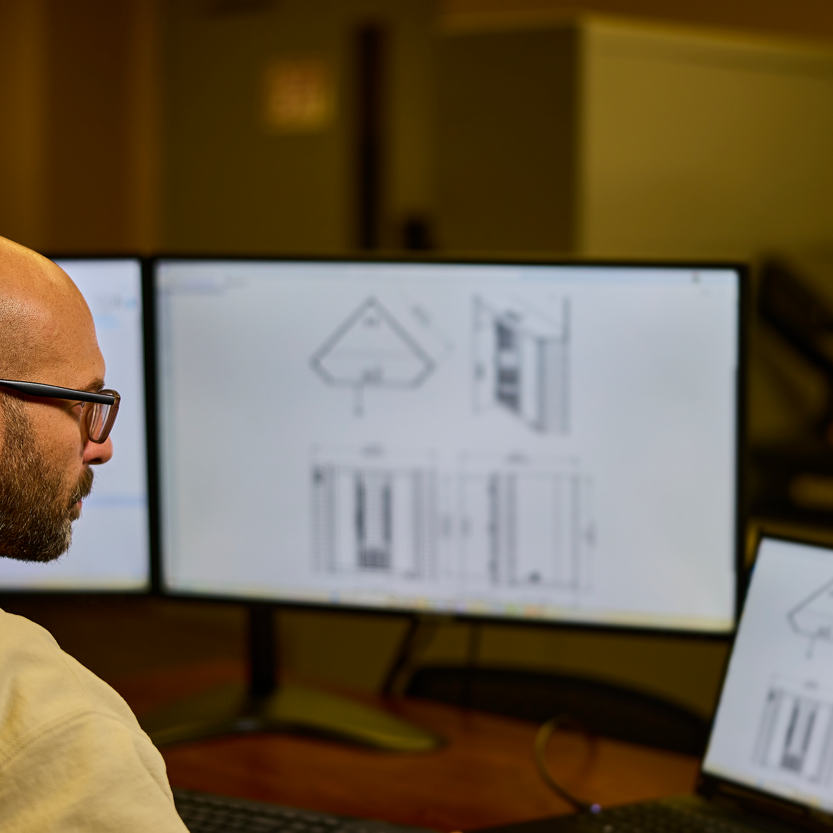 Designer reviewing technical home sauna blueprints and specifications on dual monitors