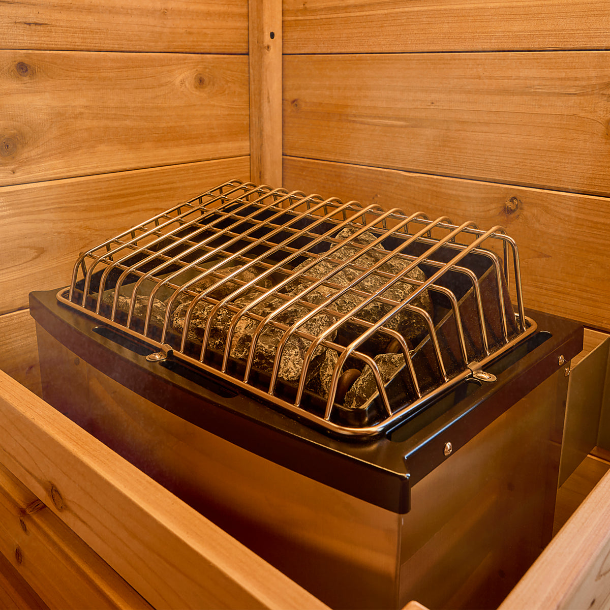 PrairieFire electric sauna heater with protective guard and stones around cedar construction